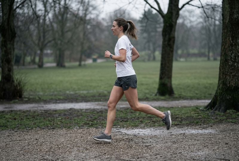 A runner training at a steady effort on a park path in early morning light